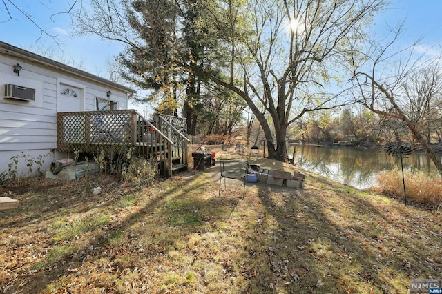 view of yard with a deck with water view and a wall mounted air conditioner