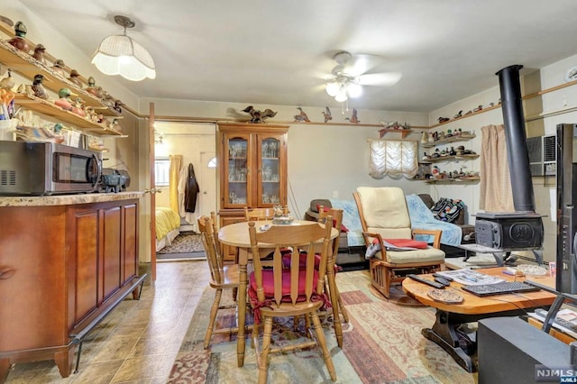 dining space featuring ceiling fan and a wood stove