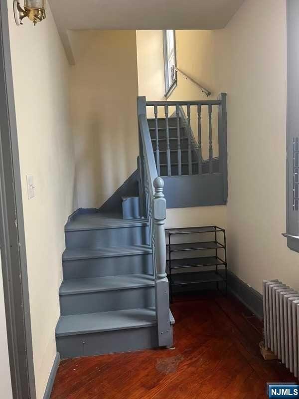 stairs with hardwood / wood-style floors and radiator