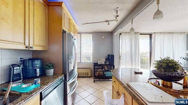 kitchen featuring decorative backsplash, a textured ceiling, appliances with stainless steel finishes, decorative light fixtures, and radiator heating unit