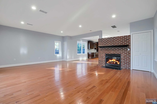 unfurnished living room featuring a brick fireplace and light wood-type flooring