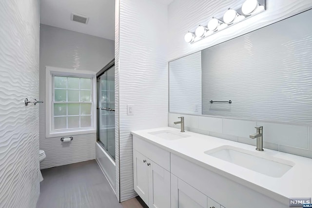 full bathroom with vanity, toilet, shower / bath combination with glass door, and tile walls