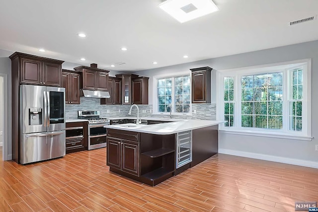 kitchen with sink, light hardwood / wood-style flooring, dark brown cabinets, kitchen peninsula, and stainless steel appliances