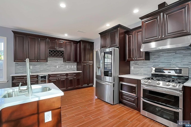 kitchen featuring decorative backsplash, appliances with stainless steel finishes, light hardwood / wood-style flooring, and sink