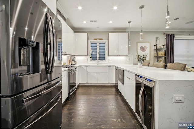 kitchen featuring decorative light fixtures, wine cooler, stainless steel appliances, and white cabinetry