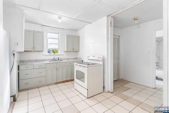 kitchen featuring light tile patterned floors, white range with electric stovetop, gray cabinetry, and sink