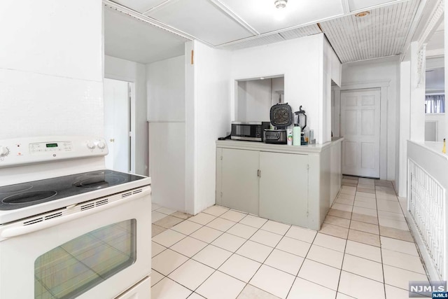 kitchen with electric stove, white cabinets, and light tile patterned floors