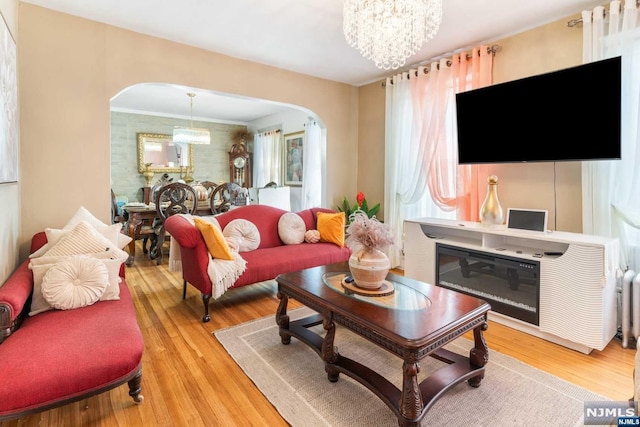 living room with ornamental molding, light wood-type flooring, and an inviting chandelier