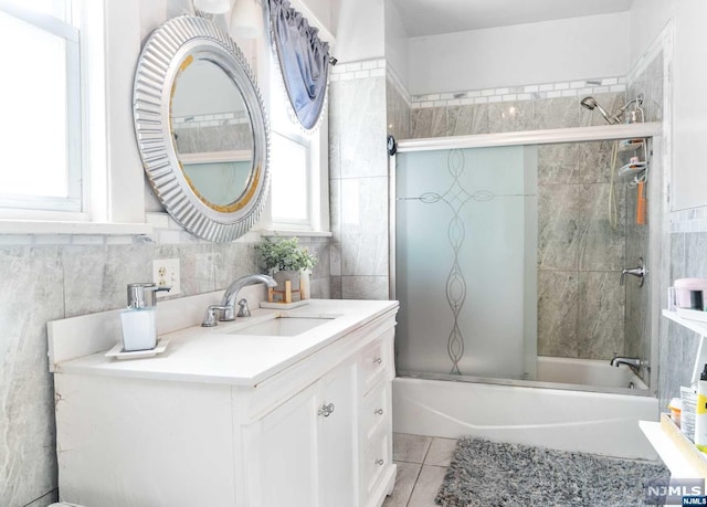 bathroom featuring tile patterned flooring, vanity, tile walls, and combined bath / shower with glass door