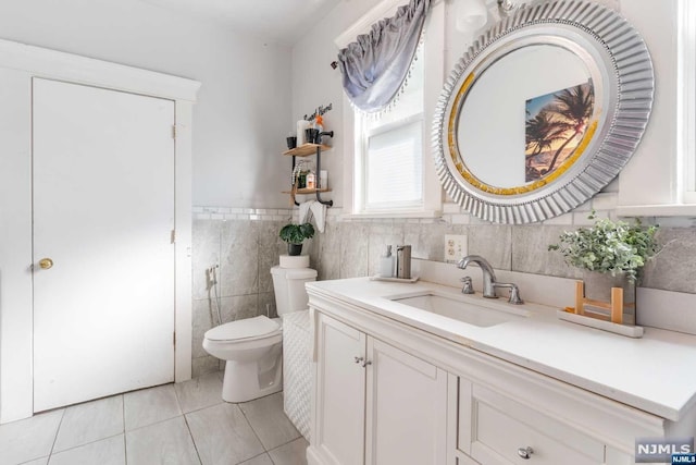 bathroom featuring tile patterned flooring, vanity, toilet, and tile walls