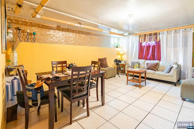 dining area with tile patterned floors and brick wall