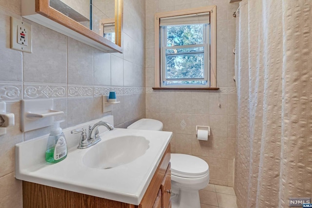 bathroom with tile patterned flooring, vanity, tile walls, and toilet