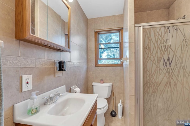 bathroom featuring tile patterned floors, walk in shower, vanity, tile walls, and toilet