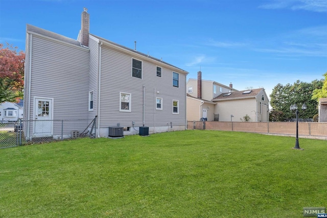 back of property featuring a lawn and central air condition unit