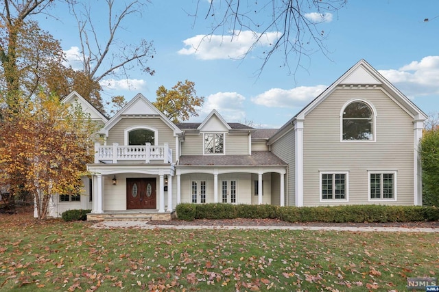 view of front of home featuring french doors, a balcony, and a front lawn