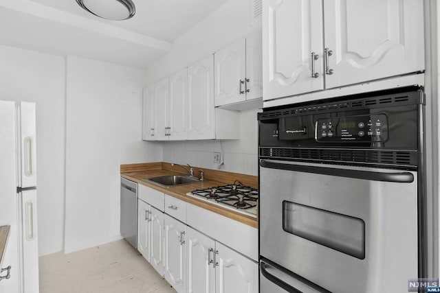 kitchen featuring sink, decorative backsplash, appliances with stainless steel finishes, light tile patterned flooring, and white cabinetry