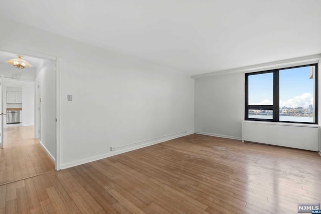 unfurnished room with a notable chandelier and light wood-type flooring