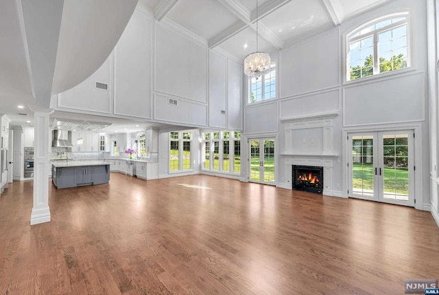 unfurnished living room featuring hardwood / wood-style flooring, a high ceiling, and a chandelier