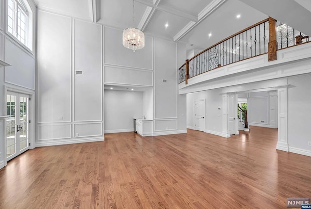 unfurnished living room with beamed ceiling, a towering ceiling, wood-type flooring, and coffered ceiling