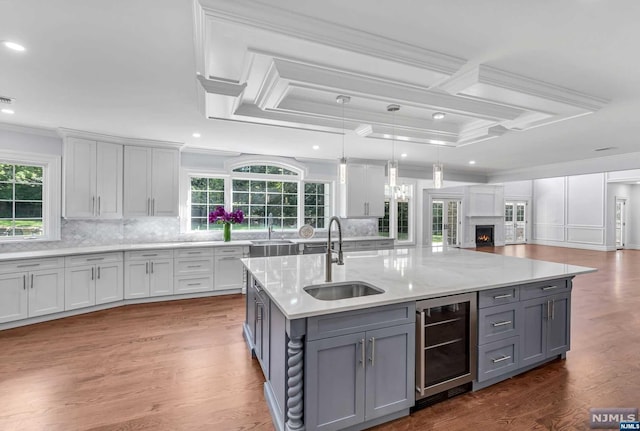 kitchen featuring pendant lighting, wine cooler, sink, and hardwood / wood-style floors