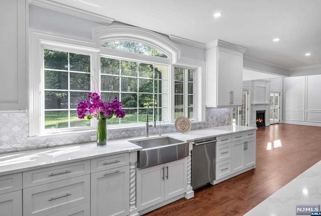 kitchen featuring a wealth of natural light, white cabinetry, dishwasher, sink, and ornamental molding