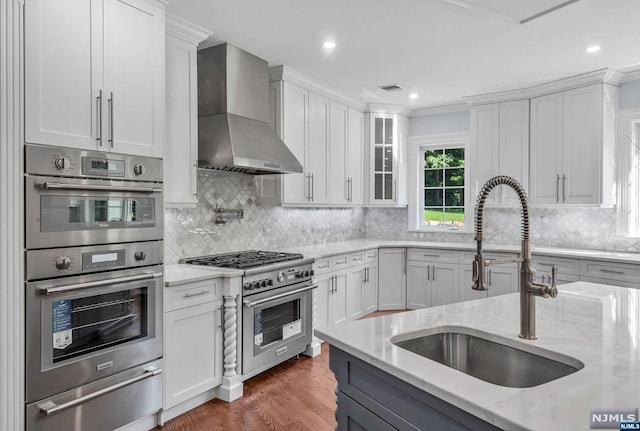 kitchen with white cabinets, stainless steel appliances, wall chimney exhaust hood, and sink