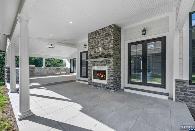 view of patio with area for grilling, french doors, and an outdoor stone fireplace