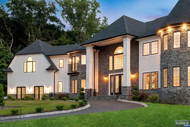 french country style house with a balcony and a yard