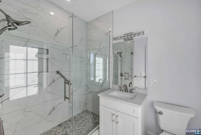 bathroom with a shower with door, vanity, and toilet