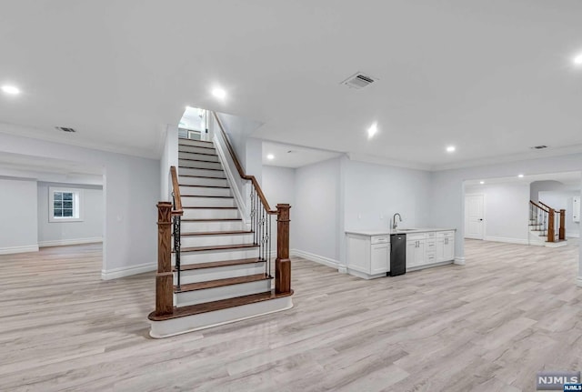 basement with light hardwood / wood-style flooring, ornamental molding, and sink