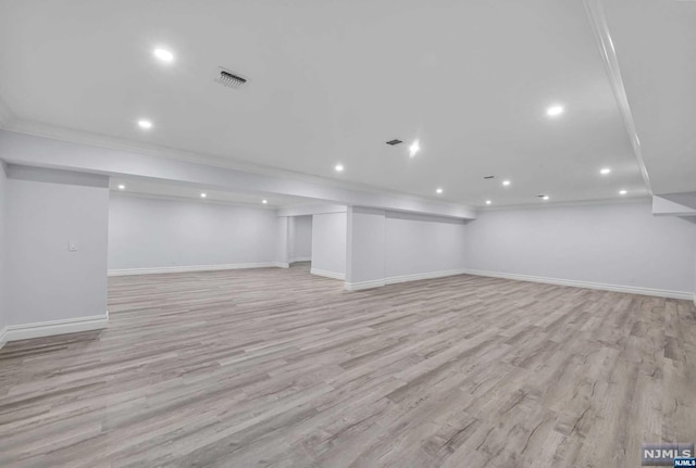 basement featuring light wood-type flooring and ornamental molding