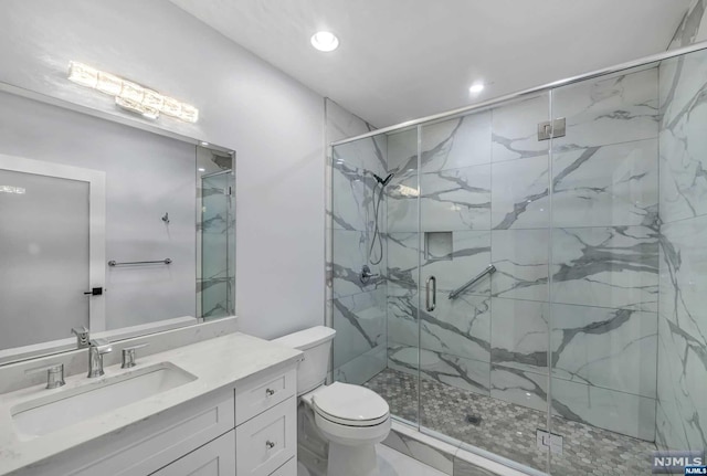 bathroom featuring vanity, toilet, and a shower with shower door