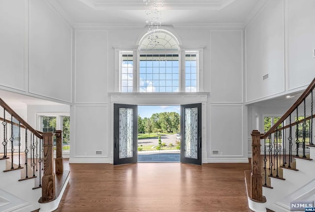 entrance foyer featuring ornamental molding, an inviting chandelier, french doors, and dark wood-type flooring