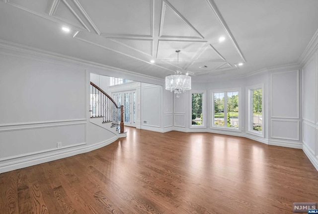 unfurnished living room with hardwood / wood-style floors, an inviting chandelier, coffered ceiling, and ornamental molding