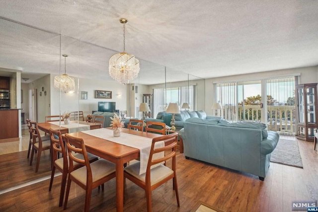 dining space with a notable chandelier, wood-type flooring, and a textured ceiling