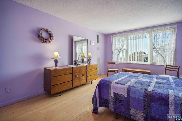 bedroom with a textured ceiling and light hardwood / wood-style floors