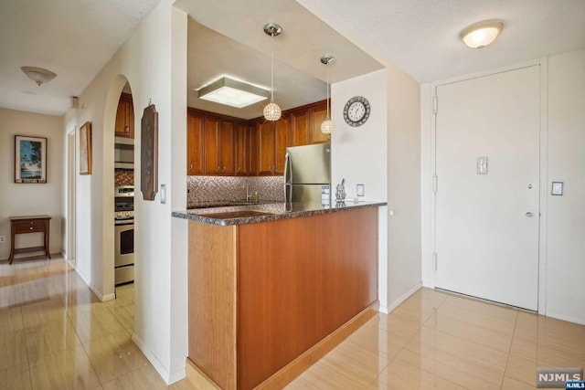 kitchen featuring a textured ceiling, decorative backsplash, pendant lighting, and stainless steel appliances