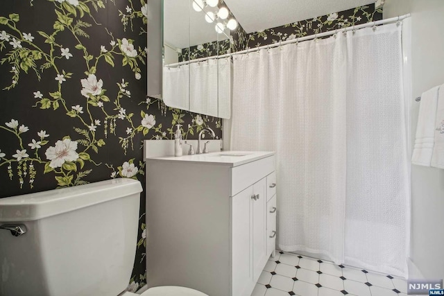 bathroom featuring a textured ceiling, vanity, and toilet