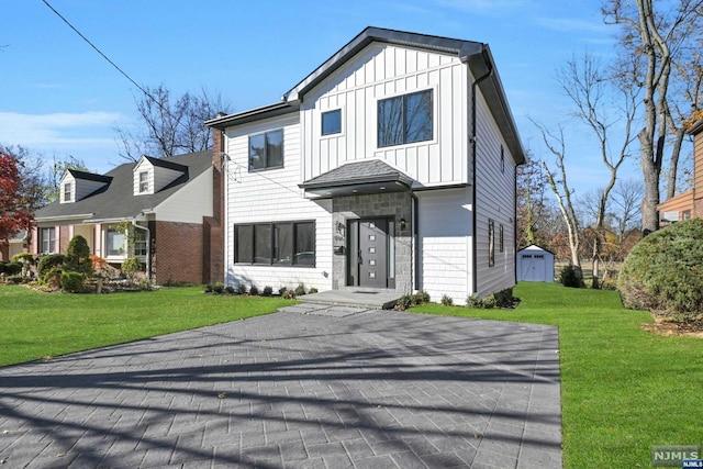 view of front of property featuring a front yard and a storage shed