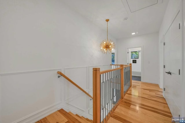 stairway featuring hardwood / wood-style flooring and a notable chandelier