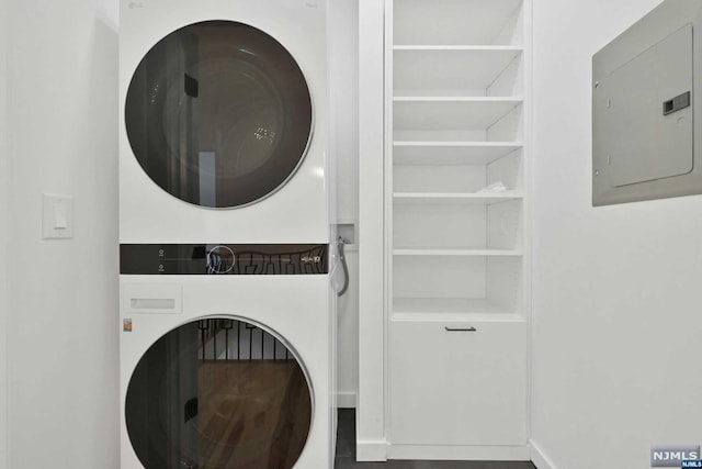 laundry area with stacked washer and dryer and electric panel