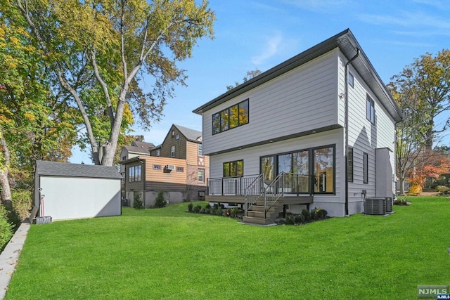 rear view of property featuring cooling unit, a shed, a yard, and a wooden deck