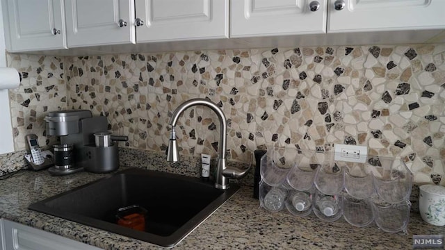 details with backsplash, sink, white cabinets, and stone countertops