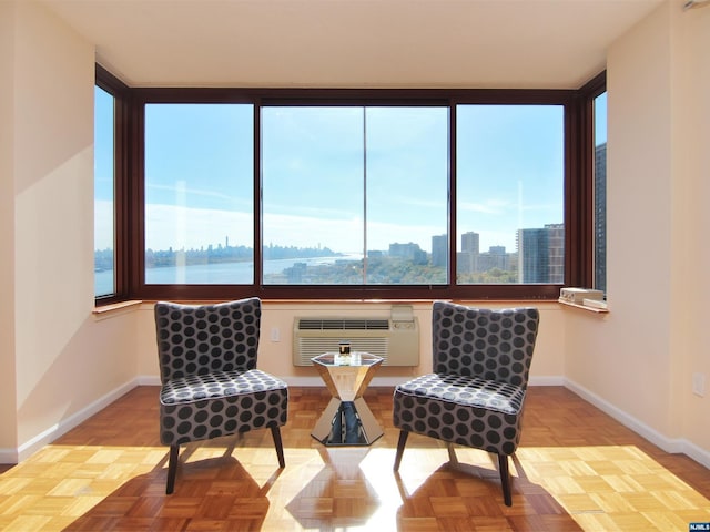 sitting room featuring a wall mounted air conditioner, plenty of natural light, a water view, and light parquet flooring