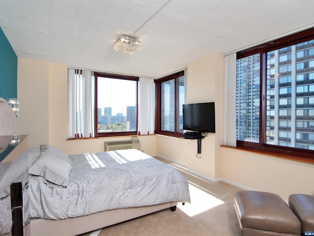 bedroom featuring a wall unit AC, a chandelier, and a textured ceiling