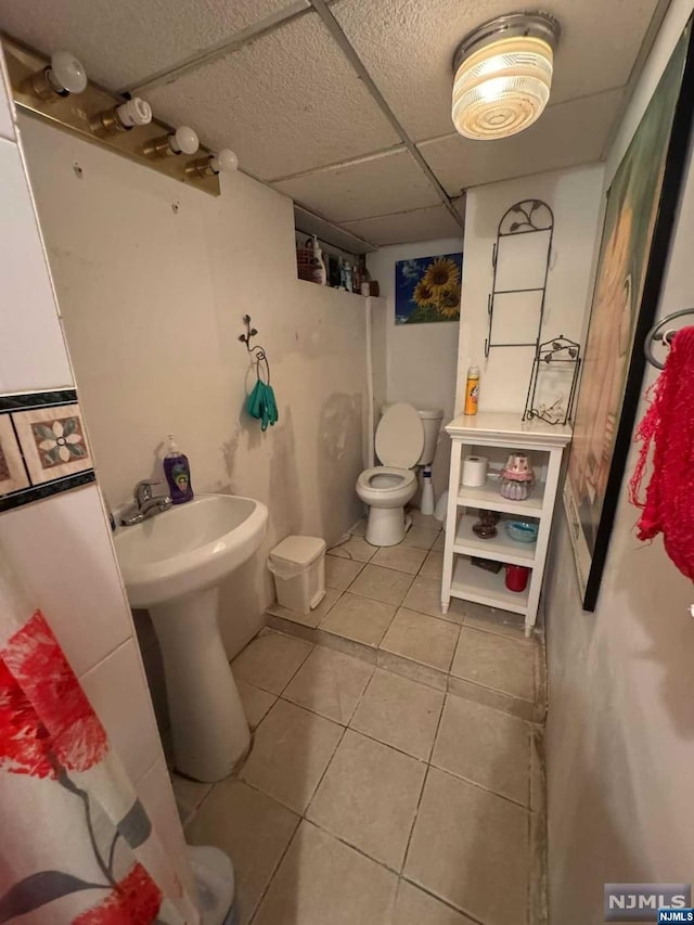 bathroom with tile patterned flooring, a paneled ceiling, and toilet