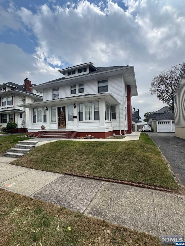 view of front of property with covered porch, a front lawn, and an outdoor structure