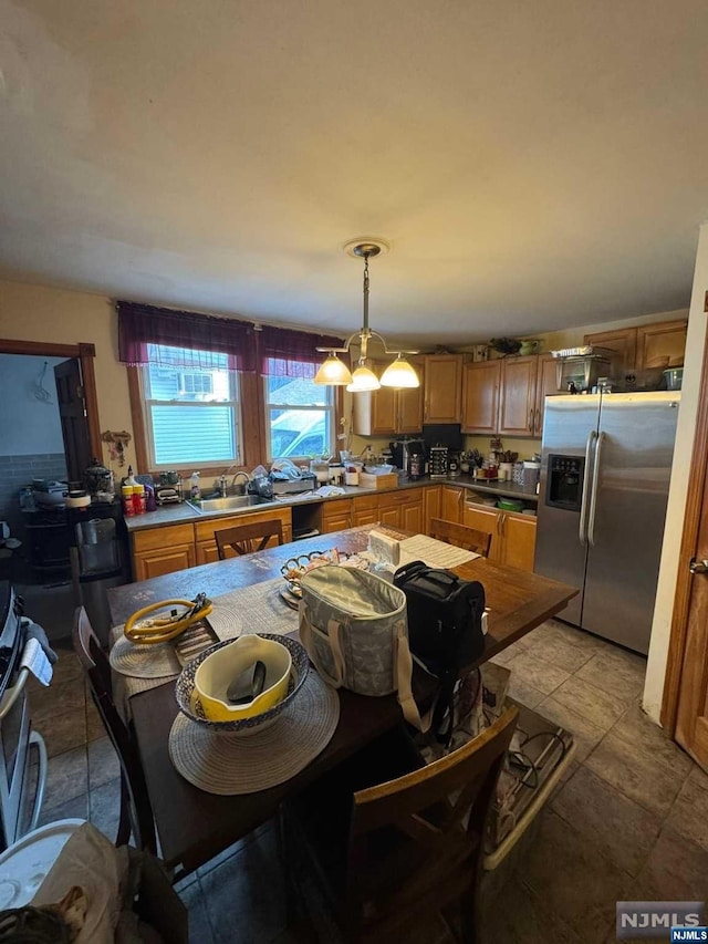 kitchen with decorative light fixtures, sink, and stainless steel refrigerator with ice dispenser