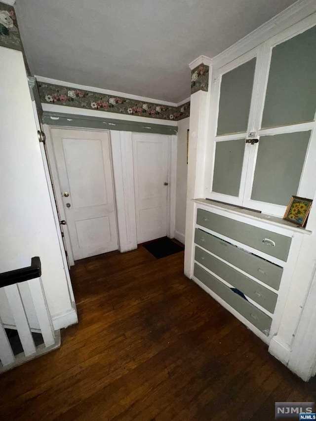 corridor with dark hardwood / wood-style flooring and ornamental molding