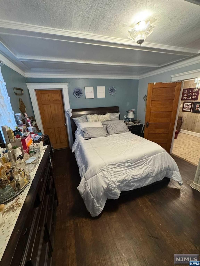 bedroom with crown molding, dark wood-type flooring, and a textured ceiling